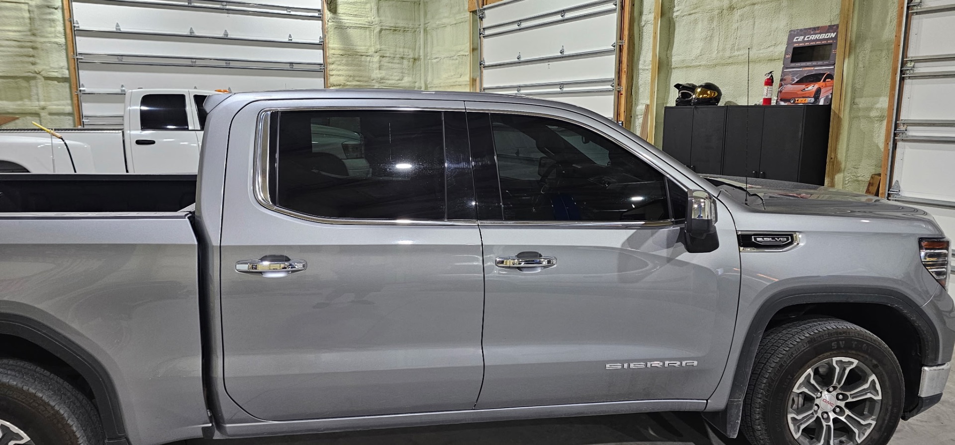Side profile of a silver GMC Sierra SLT with premium window tint