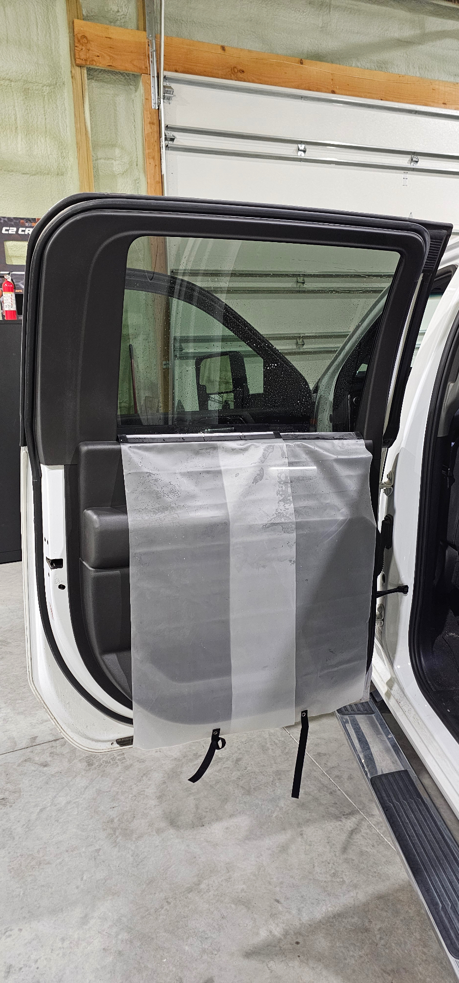 Rear door tint film being installed on a white Chevy Silverado in the Fallon shop