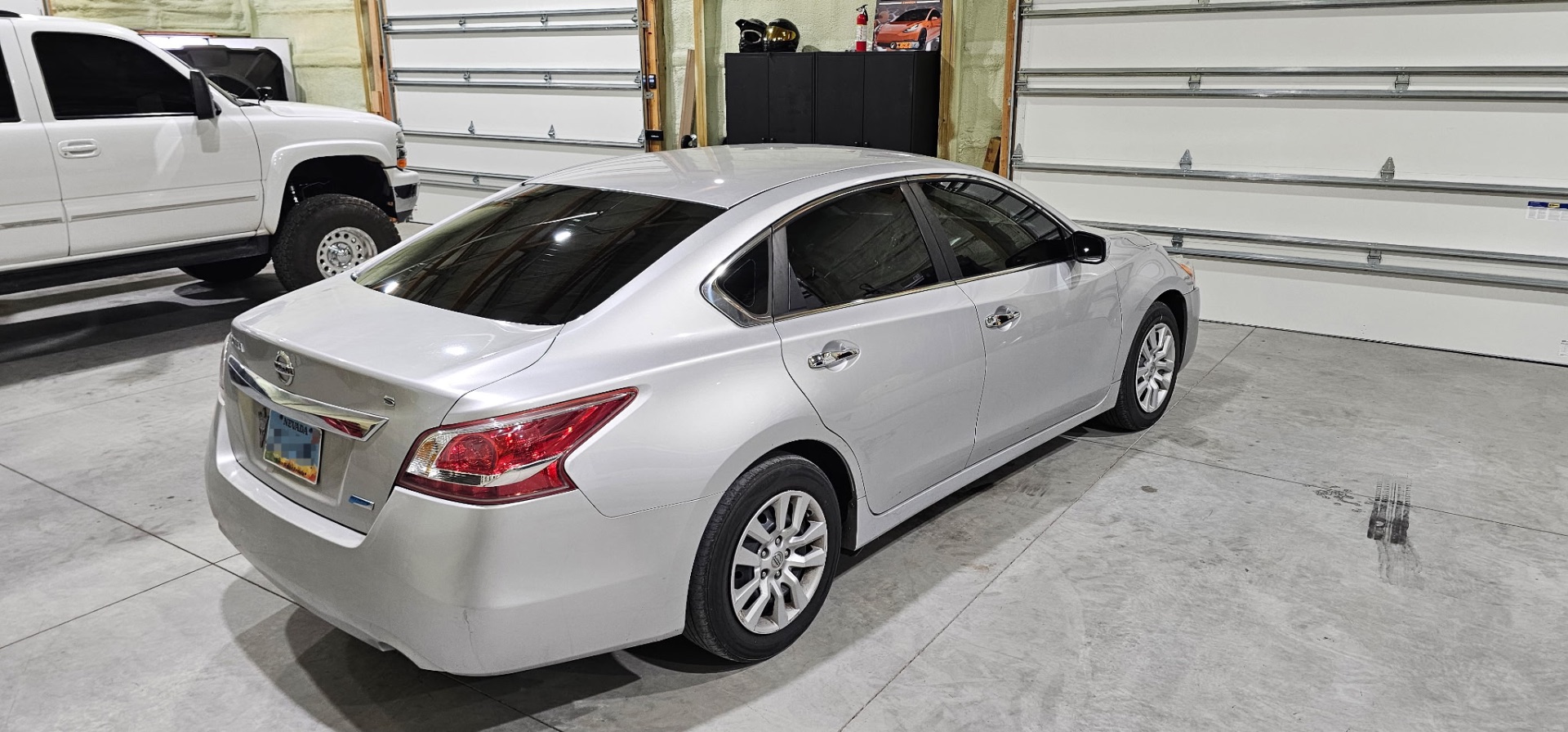 Silver Nissan Altima with fresh dark window tint parked in the High Desert Tint shop