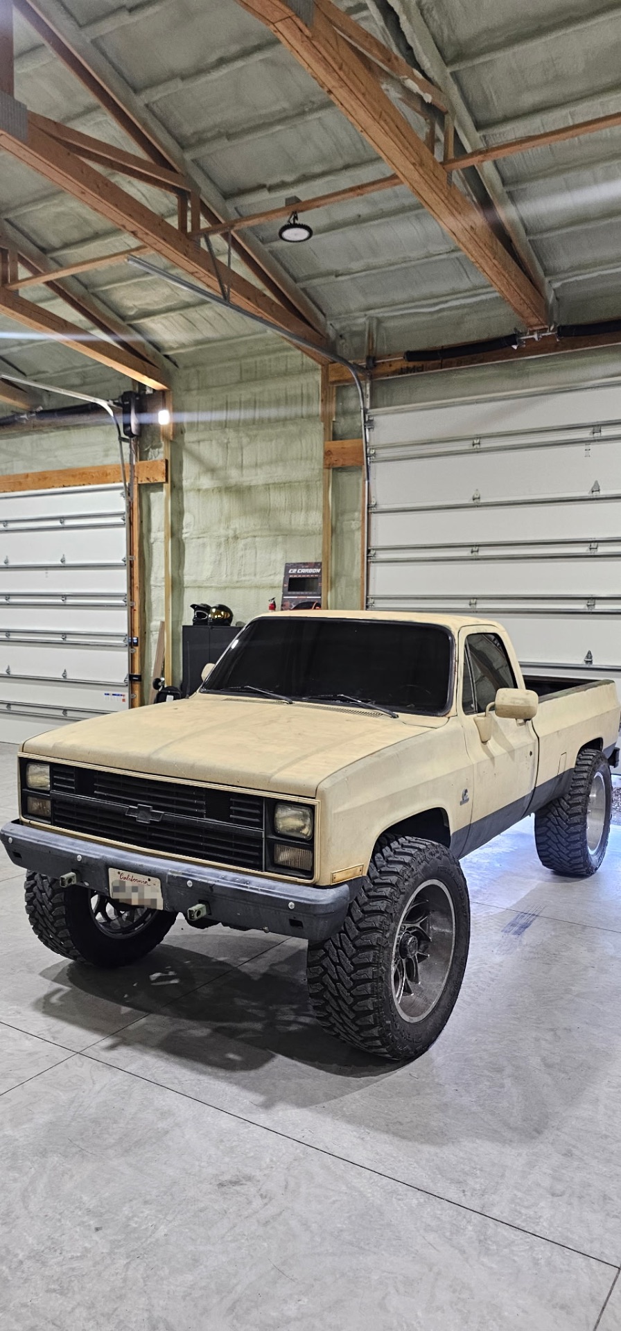 Tan square-body Chevy K10 lifted pickup with fresh window tint in the High Desert Tint shop
