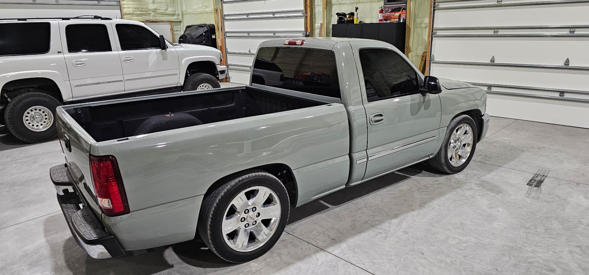 Rear view of a sage green single cab Chevy Silverado with tinted rear window in the shop